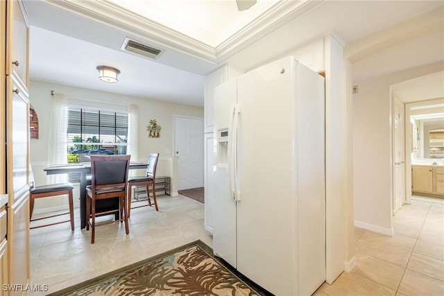 kitchen featuring white refrigerator with ice dispenser, ornamental molding, and light tile patterned flooring