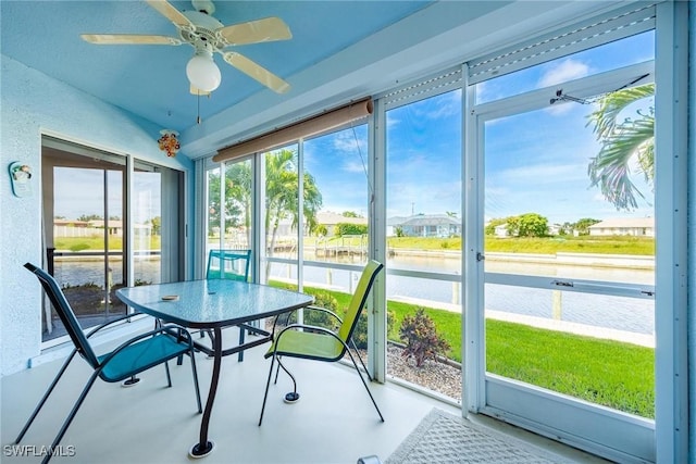 sunroom / solarium featuring ceiling fan and a water view