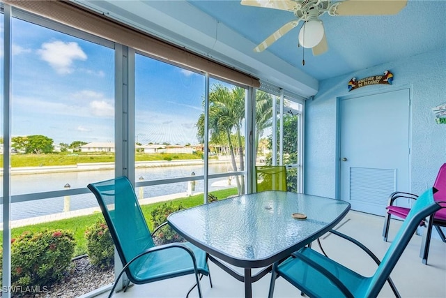 sunroom with ceiling fan and a water view