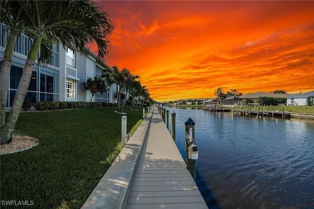 view of dock featuring a water view and a yard