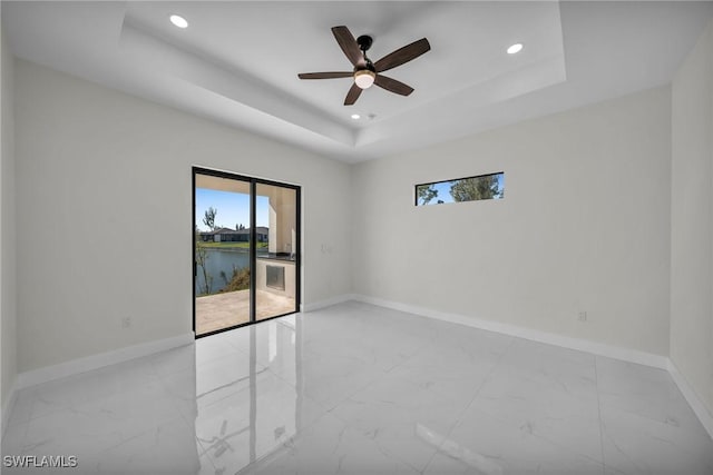 spare room with a water view, a raised ceiling, and ceiling fan