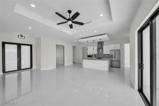 kitchen featuring stainless steel fridge, a tray ceiling, pendant lighting, white cabinets, and a kitchen island