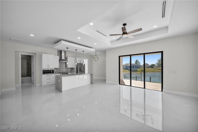 kitchen featuring white cabinetry, a center island, wall chimney exhaust hood, stainless steel appliances, and pendant lighting