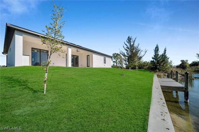 rear view of property with a lawn and ceiling fan