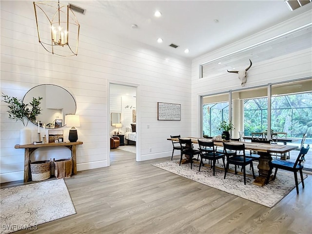 dining room featuring wood walls, a notable chandelier, and hardwood / wood-style flooring