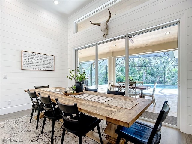 dining space featuring hardwood / wood-style floors, plenty of natural light, and wooden walls