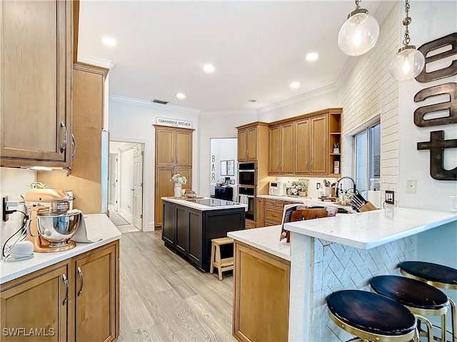 kitchen featuring kitchen peninsula, crown molding, light hardwood / wood-style floors, hanging light fixtures, and a breakfast bar area