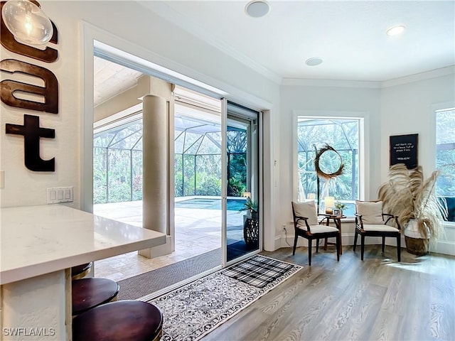 entryway featuring a healthy amount of sunlight, wood-type flooring, and crown molding