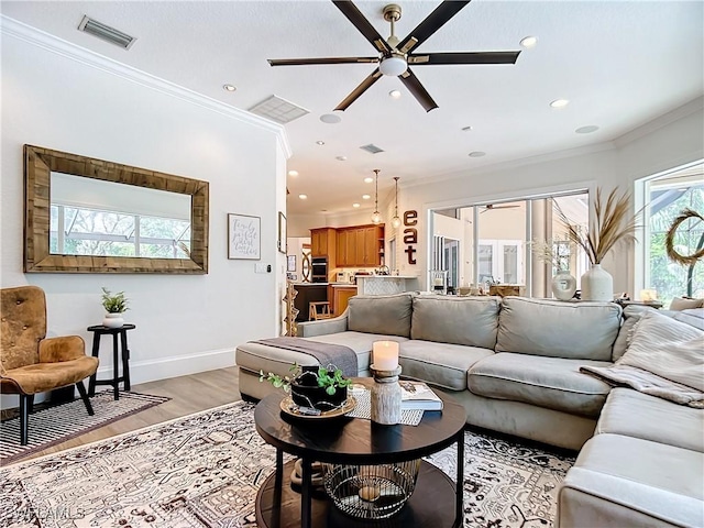 living room with ceiling fan, light hardwood / wood-style floors, and crown molding