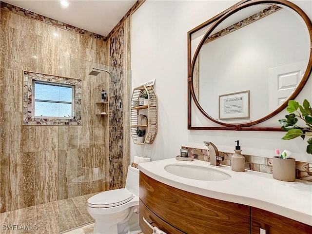 bathroom featuring vanity, toilet, and a tile shower