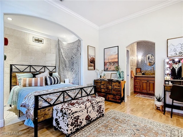 bedroom with connected bathroom, light hardwood / wood-style floors, tile walls, and crown molding