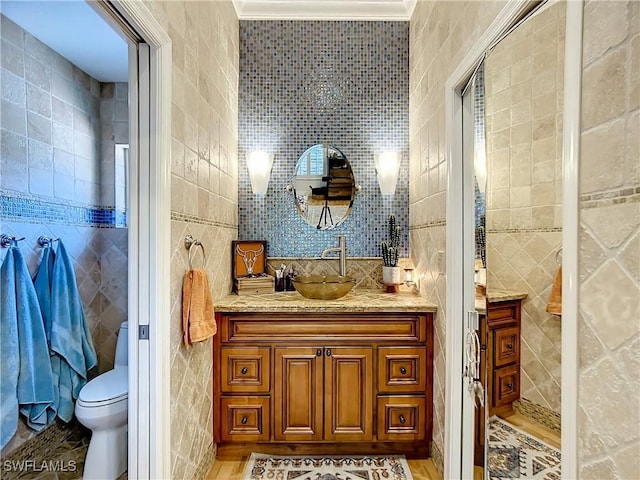 bathroom featuring vanity, ornamental molding, tile walls, and toilet