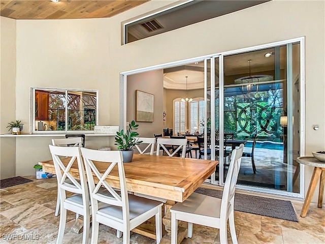 dining area with wood ceiling, a high ceiling, and a chandelier