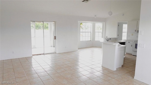 interior space with white cabinetry, light tile patterned flooring, a healthy amount of sunlight, and vaulted ceiling