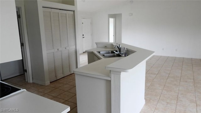 kitchen featuring light tile patterned flooring, kitchen peninsula, and sink