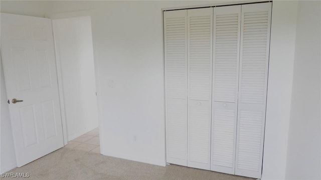 unfurnished bedroom featuring light colored carpet and a closet