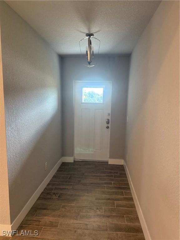 doorway featuring dark hardwood / wood-style flooring and a textured ceiling