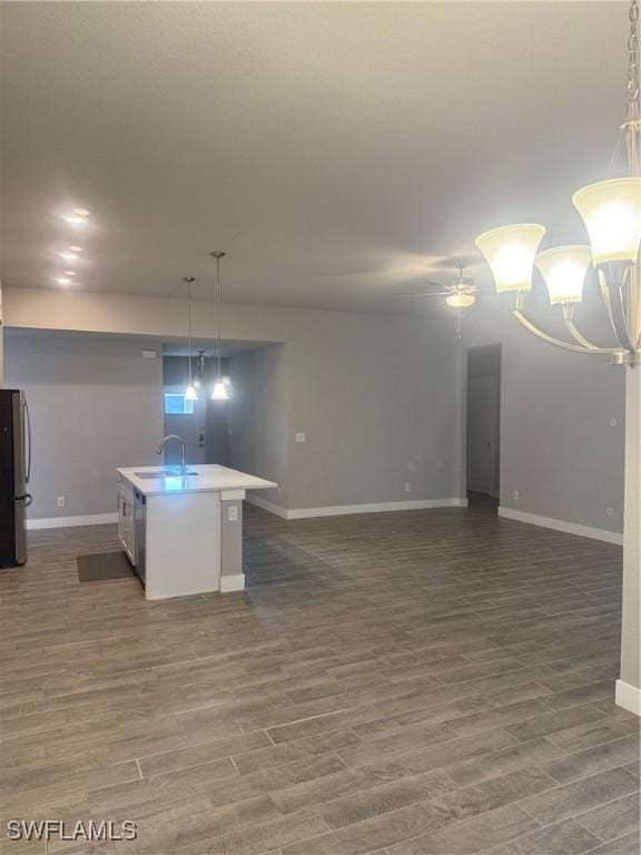 kitchen with sink, stainless steel appliances, dark hardwood / wood-style floors, an island with sink, and pendant lighting