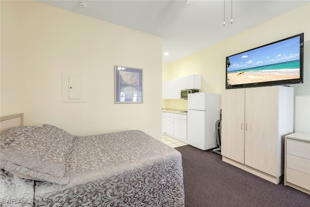 carpeted bedroom featuring ceiling fan, white fridge, and ensuite bathroom