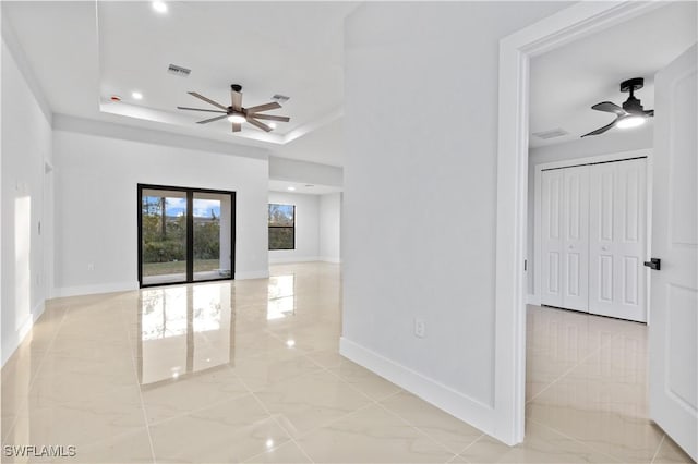 spare room featuring a tray ceiling and ceiling fan