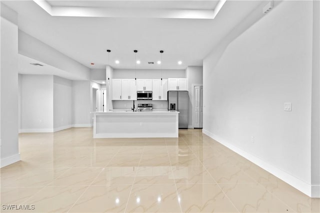 kitchen with pendant lighting, stainless steel appliances, white cabinetry, and an island with sink