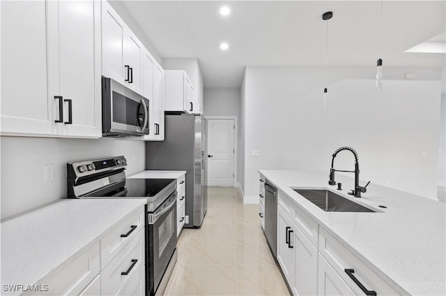 kitchen with sink, light stone countertops, appliances with stainless steel finishes, decorative light fixtures, and white cabinetry