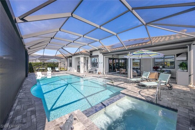 view of swimming pool with a lanai, a patio area, and an in ground hot tub