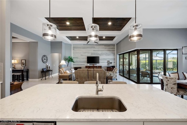 kitchen featuring decorative light fixtures, light stone counters, and an island with sink