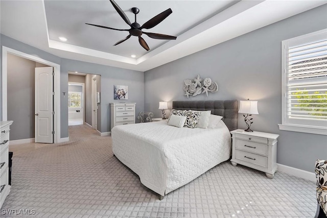 bedroom with a tray ceiling, ceiling fan, and light colored carpet