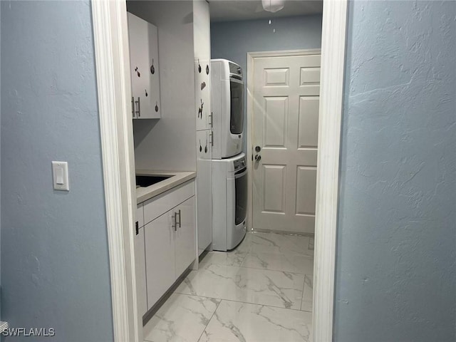 laundry area with cabinets and stacked washer / drying machine