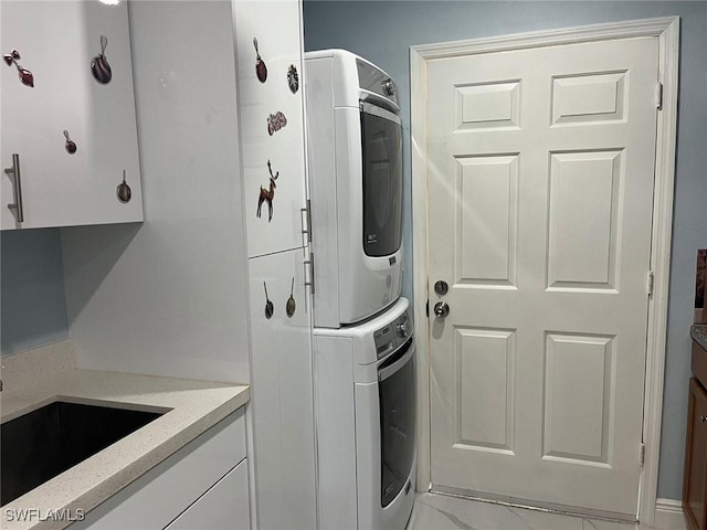 washroom featuring cabinets and stacked washer and clothes dryer