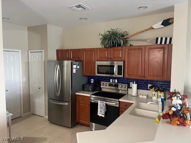 kitchen featuring sink, decorative backsplash, stainless steel appliances, and light tile patterned floors