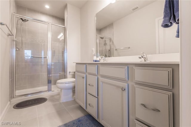 bathroom featuring toilet, vanity, tile patterned floors, and a shower with door