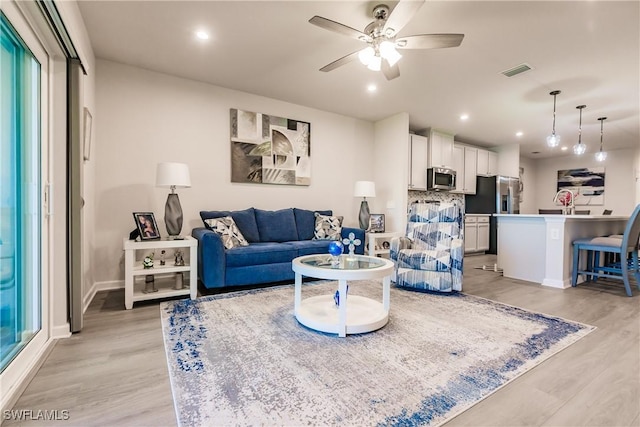 living room featuring ceiling fan and light hardwood / wood-style flooring