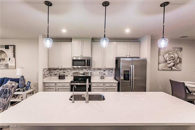 kitchen featuring decorative backsplash, sink, stainless steel appliances, and an island with sink