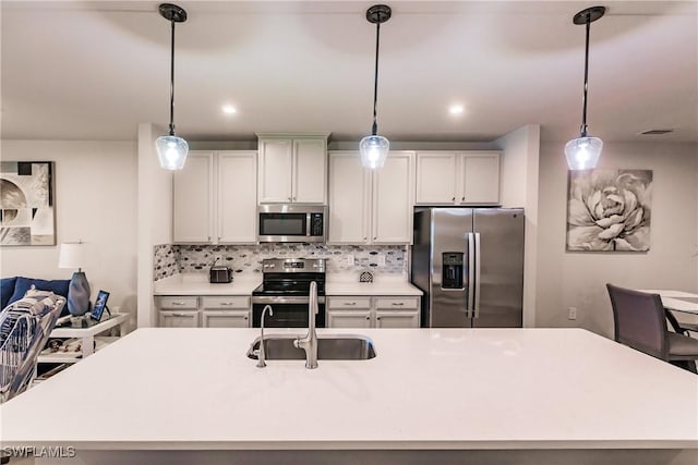16351 Coconut Palm Dr, Port Charlotte, FL 33953 - kitchen featuring stainless steel appliances, a kitchen island with sink, light countertops, decorative backsplash, and hanging light fixtures