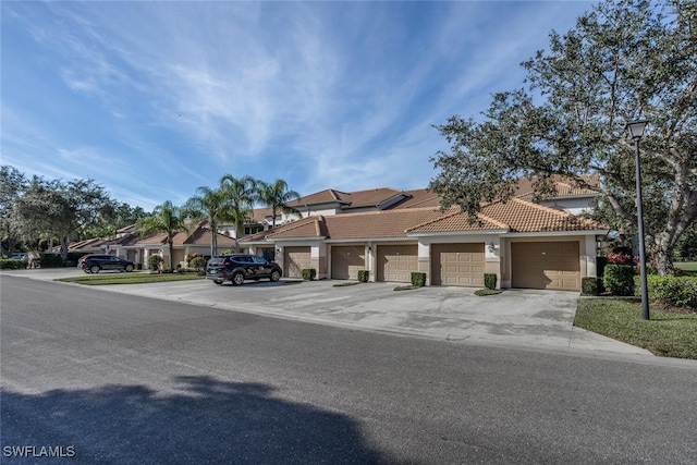 multi unit property featuring community garages, a tiled roof, and stucco siding