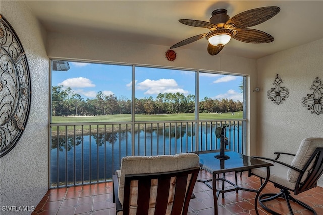 sunroom / solarium featuring ceiling fan and a water view