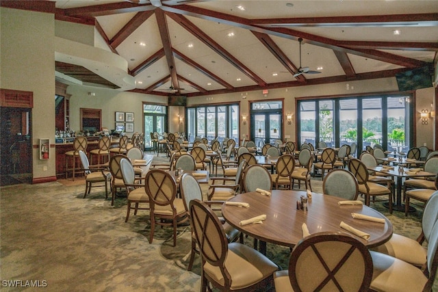 carpeted dining space with high vaulted ceiling and beamed ceiling