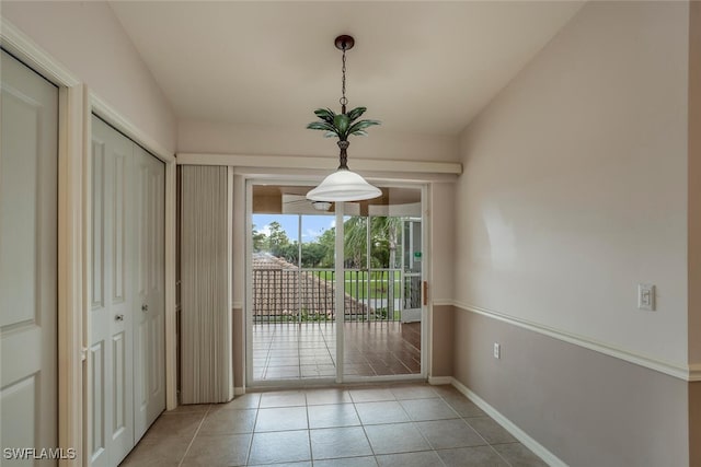 doorway with baseboards and light tile patterned floors