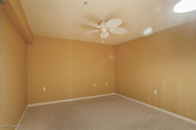 carpeted empty room featuring ceiling fan and baseboards