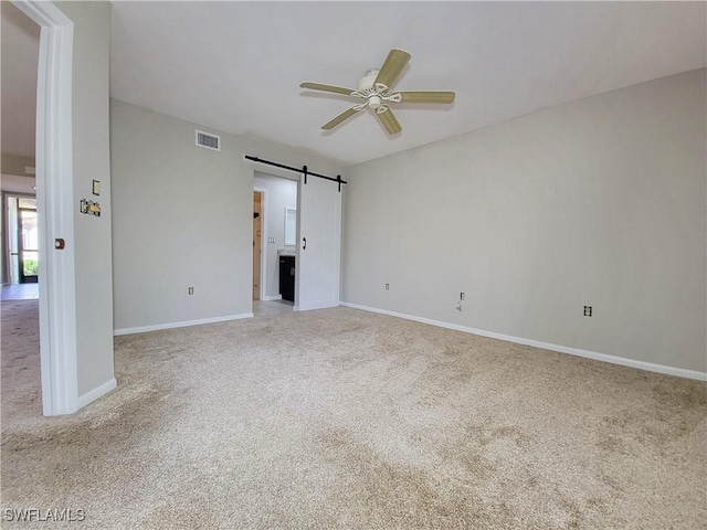 interior space with light carpet, ceiling fan, and a barn door