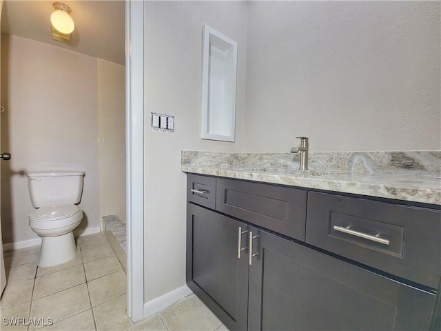 bathroom with toilet, vanity, and tile patterned flooring