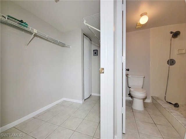 bathroom with a tile shower, tile patterned floors, and toilet