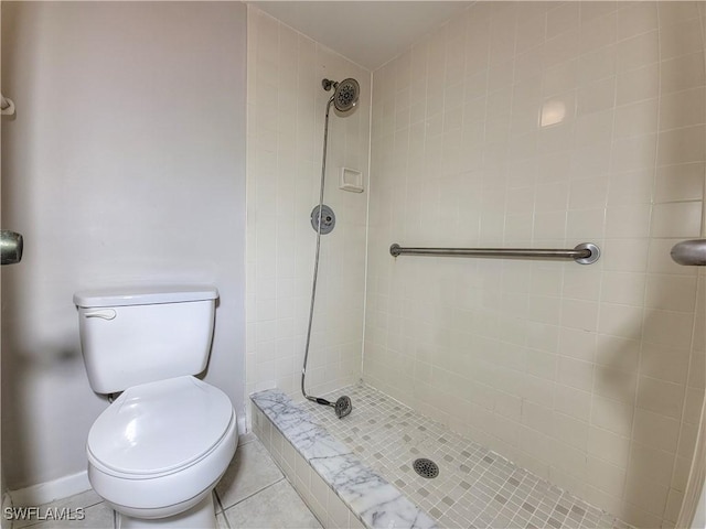 bathroom featuring tile patterned flooring, a tile shower, and toilet