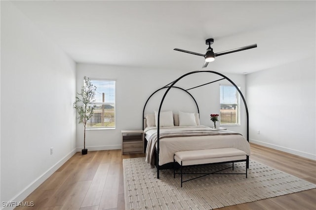 bedroom with light wood-type flooring, multiple windows, and ceiling fan