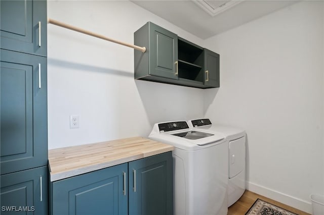 laundry area featuring cabinets, hardwood / wood-style flooring, and washing machine and clothes dryer