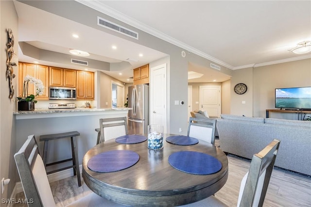 dining space featuring ornamental molding and light wood-type flooring