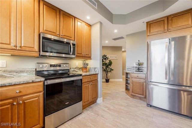 kitchen with light stone counters, light tile patterned flooring, and stainless steel appliances