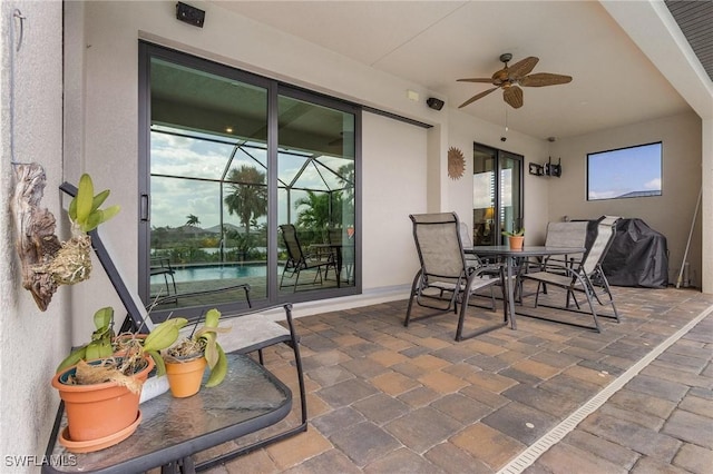 view of patio featuring ceiling fan, a lanai, and a water view